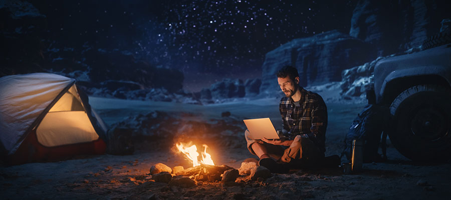 un hombre acampando en el exterior utilizando una notebook